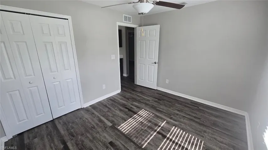 Unfurnished bedroom featuring dark wood finished floors, a closet, and a ceiling fan