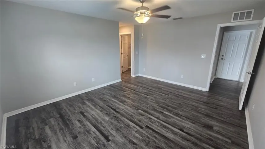 Unfurnished bedroom featuring dark wood-type flooring and ceiling fan