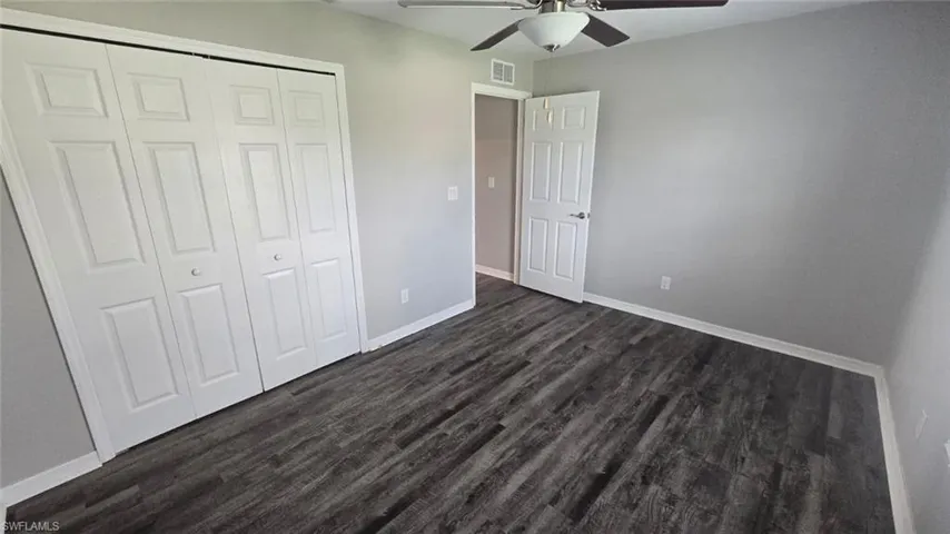 Unfurnished bedroom featuring dark wood-type flooring, a closet, and ceiling fan