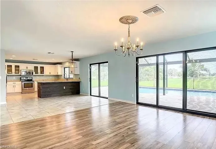 Unfurnished living room featuring sink, an inviting chandelier, and light wood-type flooring