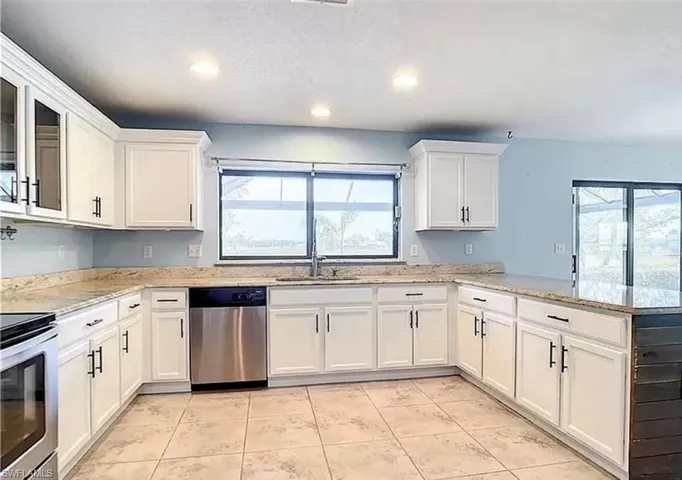 Kitchen with light tile patterned flooring, dishwasher, a healthy amount of sunlight, and kitchen peninsula