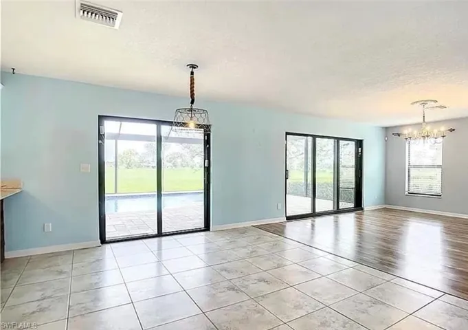 Spare room with a notable chandelier, a textured ceiling, and light tile patterned floors