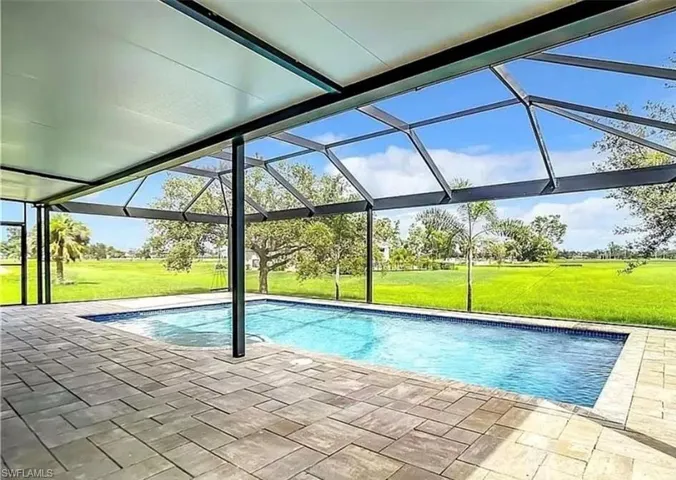 View of pool featuring glass enclosure, a patio area, and a yard