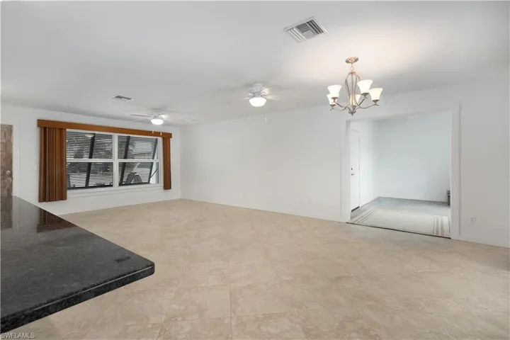 Unfurnished living room featuring ceiling fan with notable chandelier