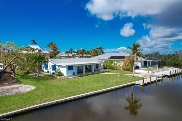 Back of property featuring a water view, glass enclosure, and a lawn