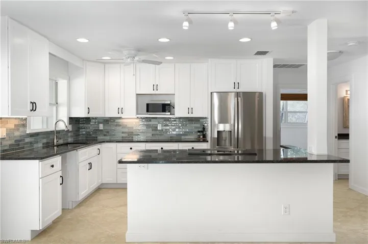 Kitchen with sink, white cabinets, dark stone counters, and appliances with stainless steel finishes