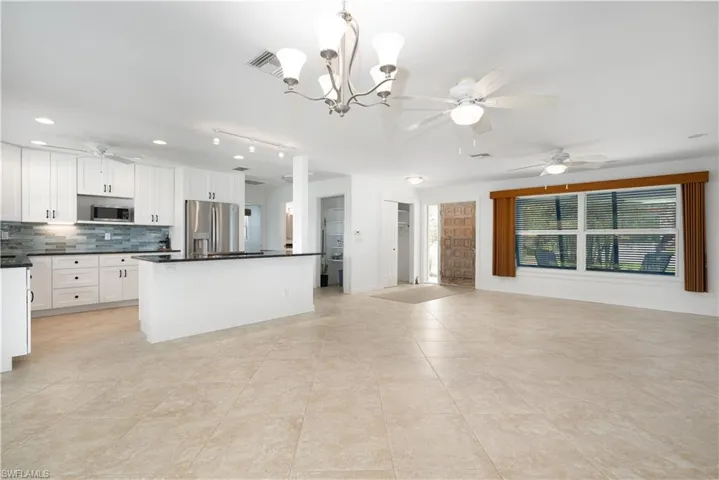 Kitchen with appliances with stainless steel finishes, tasteful backsplash, pendant lighting, white cabinets, and a kitchen island