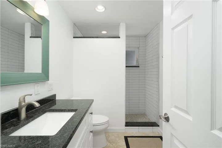 Master bathroom featuring tile patterned floors, vanity, toilet, and tiled shower