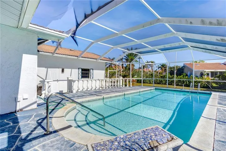 View of swimming pool with a screened cage and adjacent patio