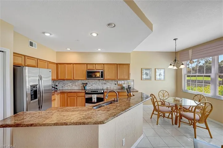 Kitchen featuring appliances with stainless steel finishes, a sink, decorative backsplash, and light tile patterned floors