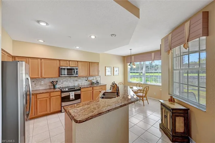 Kitchen featuring appliances with stainless steel finishes, a sink, decorative backsplash, and light tile patterned floors