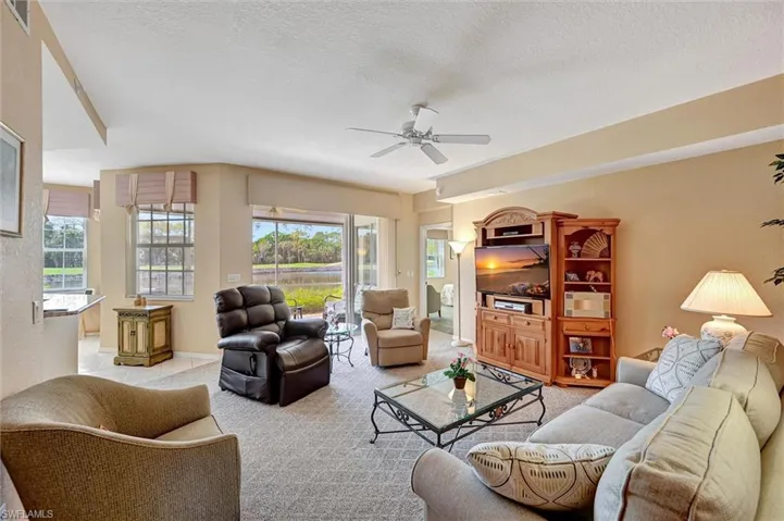 Living area with plenty of natural light, a ceiling fan, a textured ceiling, and light colored carpet