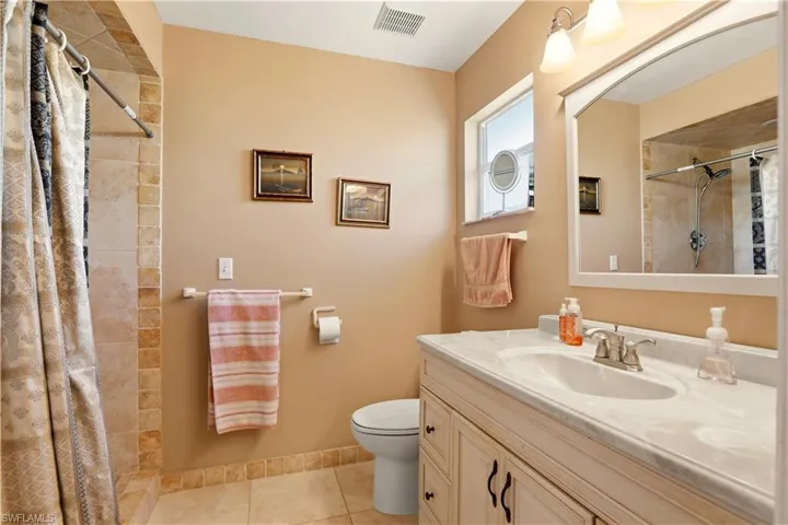 Bathroom featuring tiled shower, vanity, and light tile patterned floors
