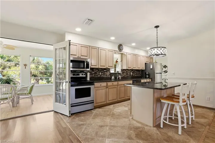 Kitchen with stainless steel appliances, hanging light fixtures, a center island, dark stone countertops, and a kitchen breakfast bar