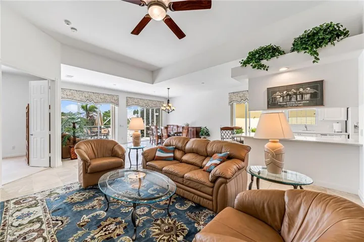 Living room with light tile floors and ceiling fan with notable chandelier