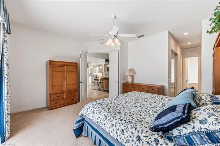 Carpeted bedroom with ceiling fan and ensuite bath