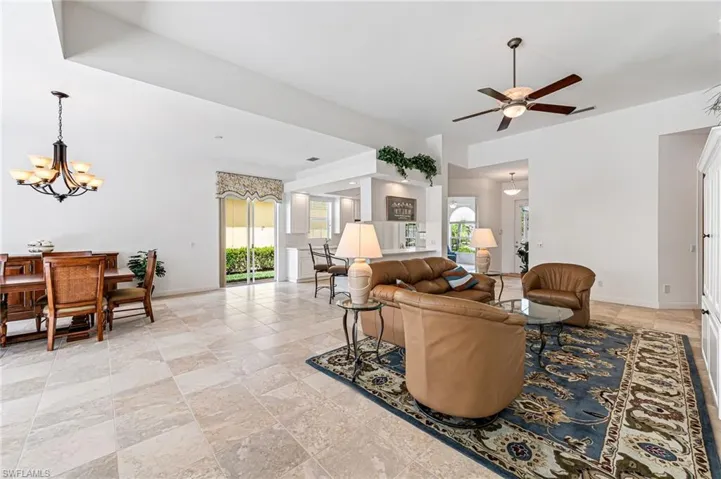 Living room featuring ceiling fan with notable chandelier and light tile floors