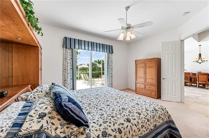 Tiled bedroom featuring access to exterior and ceiling fan with notable chandelier