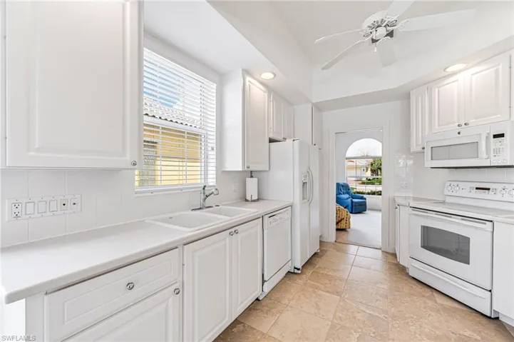 Kitchen featuring tasteful backsplash, white cabinetry, light colored carpet, sink, and white appliances