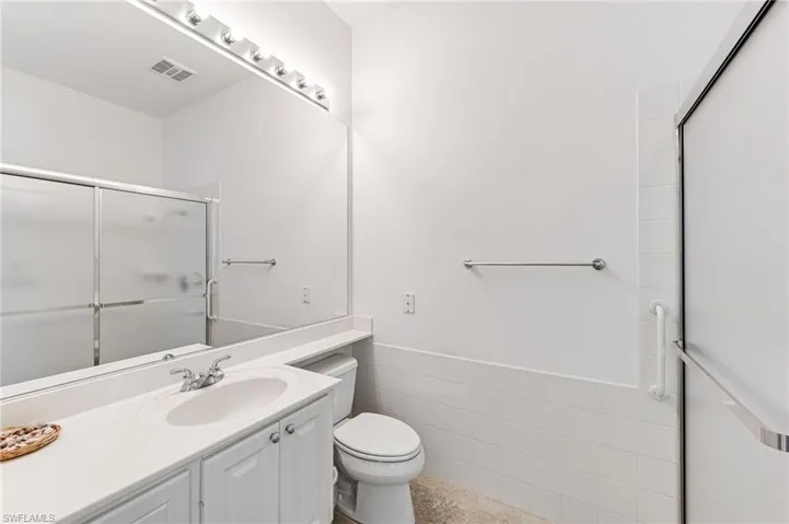 Bathroom featuring tile walls, tile flooring, large vanity, and toilet