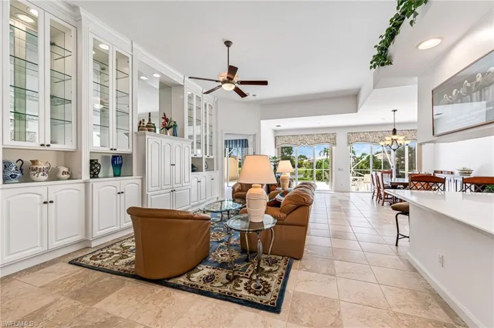 Living room featuring light tile flooring and ceiling fan with notable chandelier