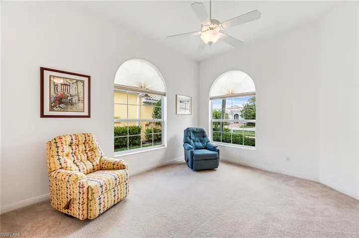 Living area with a healthy amount of sunlight, lofted ceiling, carpet, and ceiling fan