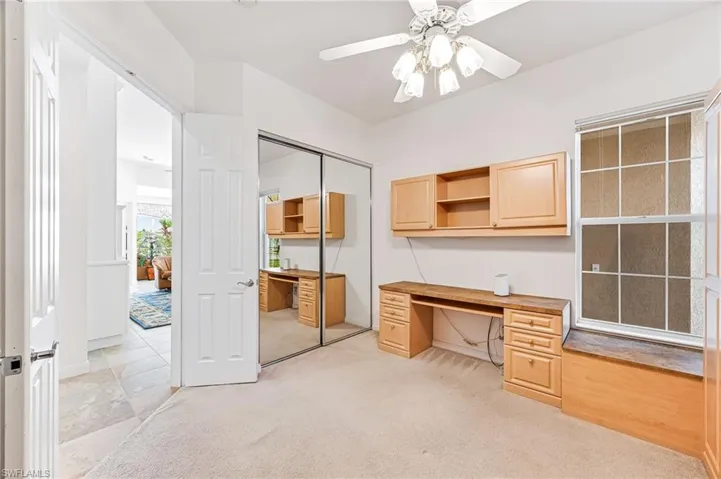 Office area with light colored carpet, built in desk, and ceiling fan
