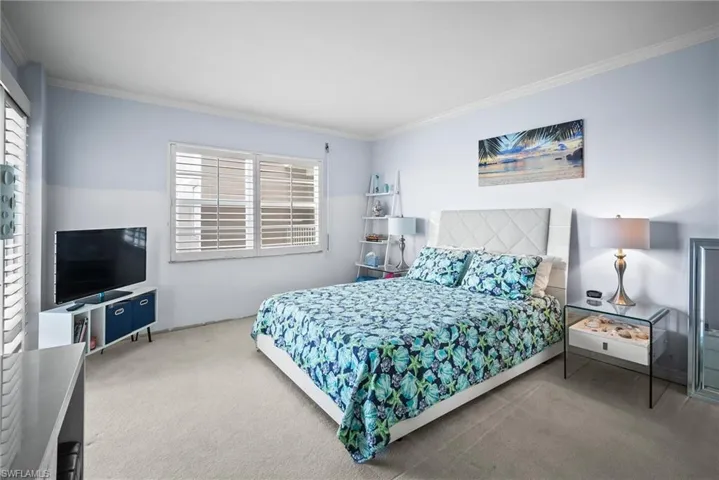 Carpeted bedroom with multiple windows and crown molding