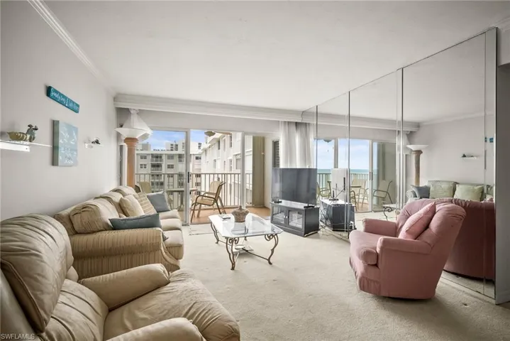Carpeted living area with ornamental molding, healthy amount of natural light, and decorative columns