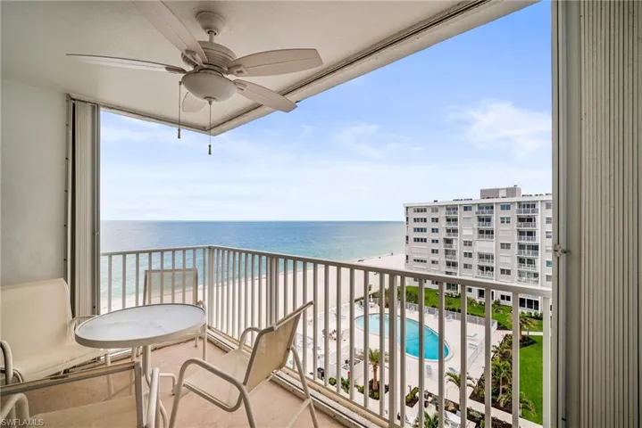 Balcony with view of pool area, a water view, and ceiling fan