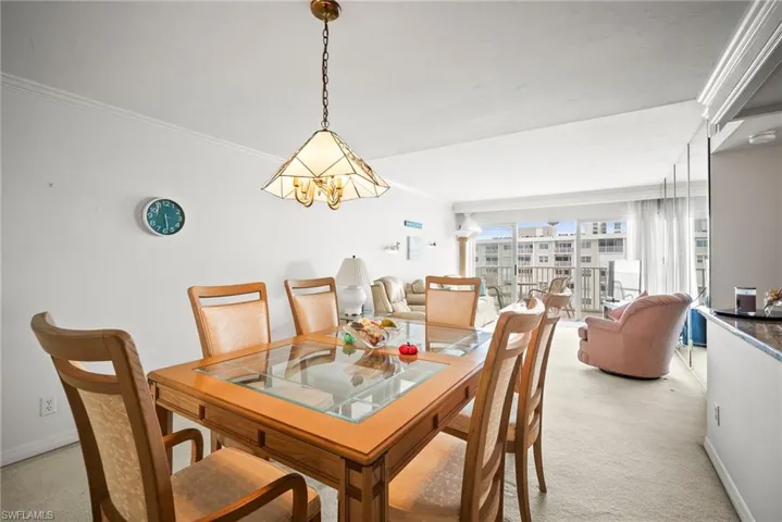 Dining space with light colored carpet, crown molding, and a chandelier