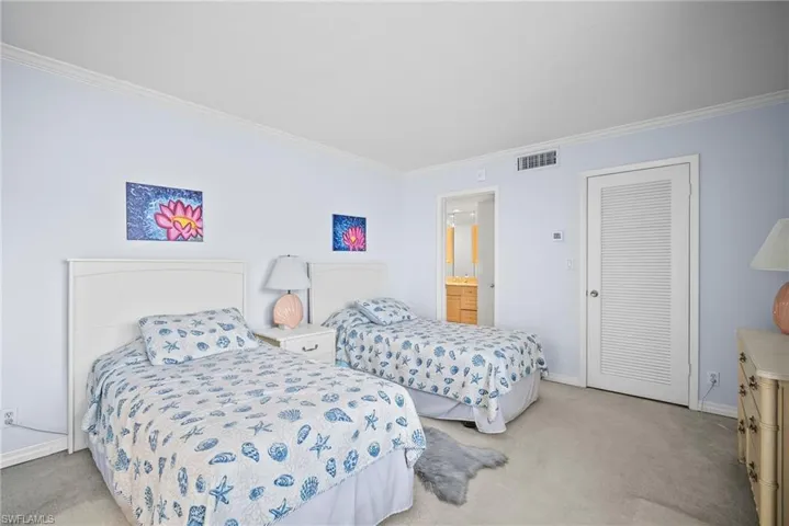 Bedroom with light carpet, crown molding, and connected bathroom