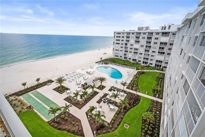 Drone / aerial view of waterfront with a beach and a pool area