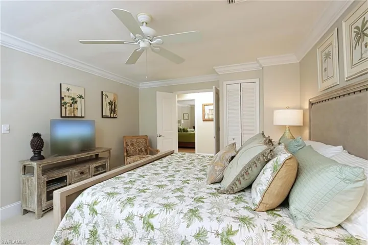 Bedroom with ceiling fan, ornamental molding, a closet, and light carpet