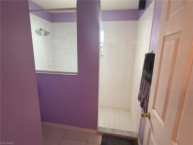 Bathroom with a tile shower, tile patterned floors, and baseboards