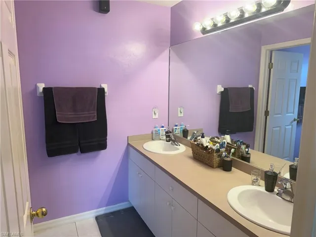 Bathroom featuring tile patterned flooring, double vanity, and baseboards