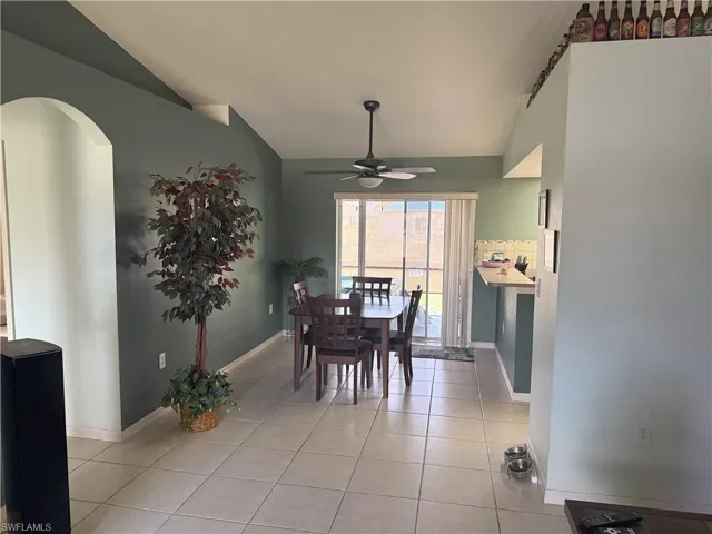 Dining space featuring ceiling fan, lofted ceiling, light tile patterned floors, and baseboards