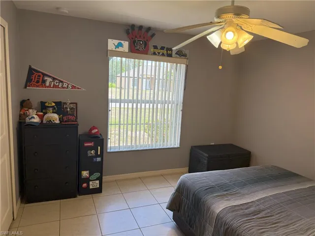 Bedroom featuring light tile patterned floors, baseboards, and a ceiling fan