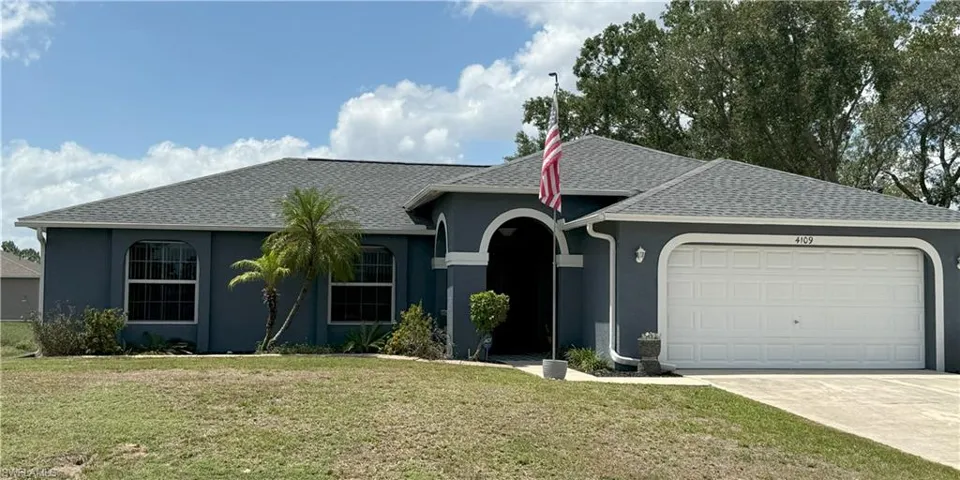Single story home with an attached garage, stucco siding, a front lawn, and a shingled roof