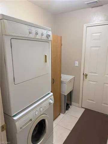 Laundry area featuring stacked washer / dryer and light tile patterned floors