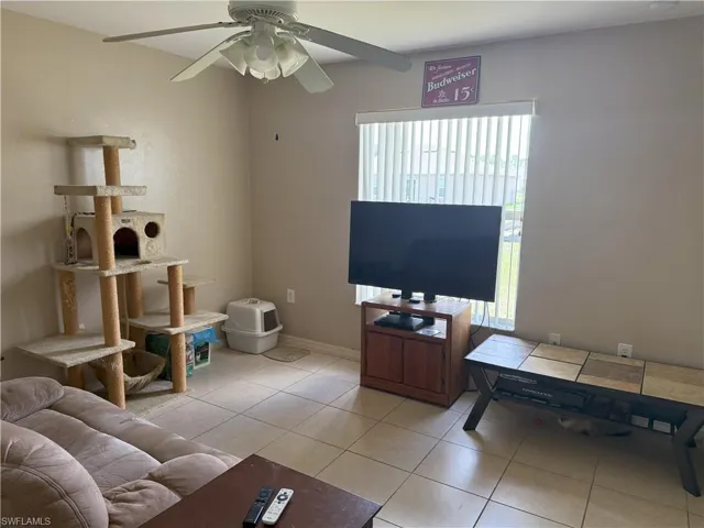 Living area with healthy amount of natural light, a ceiling fan, and light tile patterned flooring
