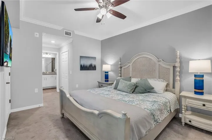 Carpeted bedroom featuring connected bathroom, ceiling fan, and crown molding