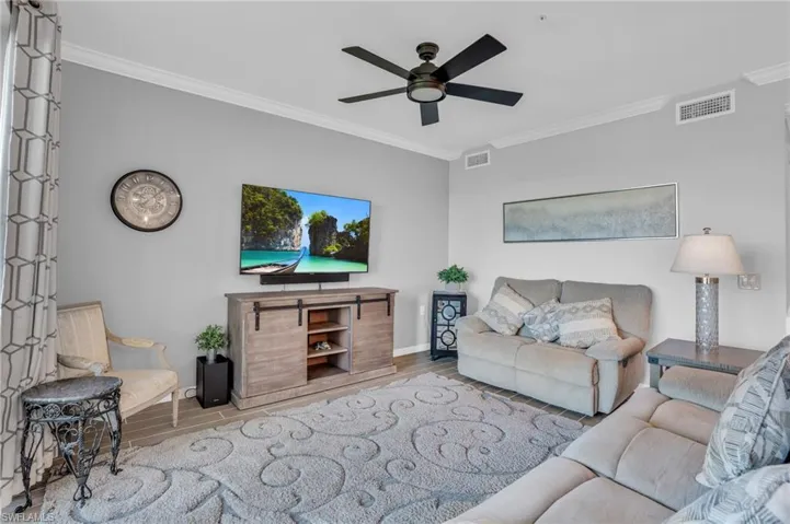 Living room with ornamental molding, and ceiling fan