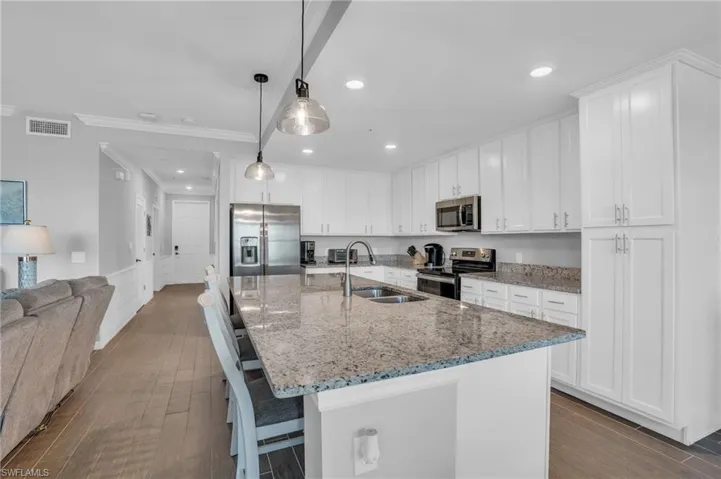 Kitchen with white cabinetry, an island with sink, appliances with stainless steel finishes