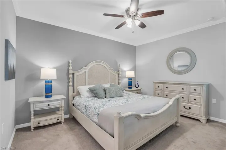 Carpeted bedroom with ornamental molding and ceiling fan