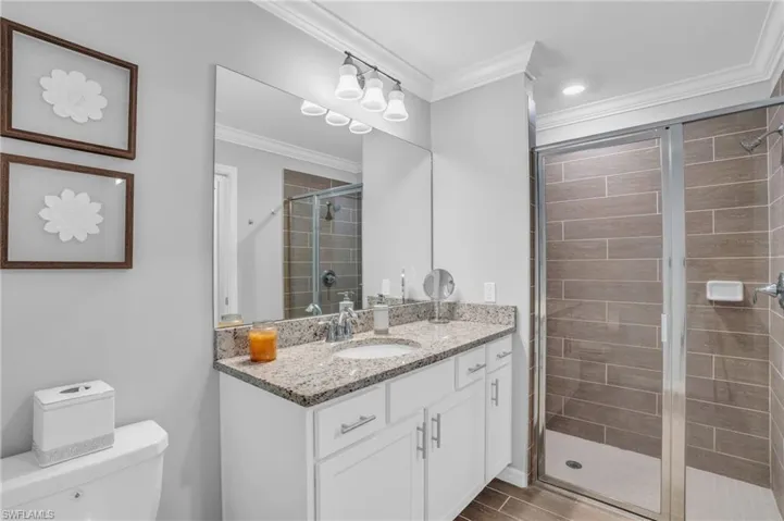 Bathroom with vanity with extensive cabinet space, ornamental molding, and a glass shower door