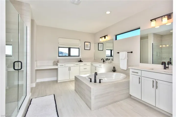 Full bath with a bath, a shower stall, two vanities, and recessed lighting