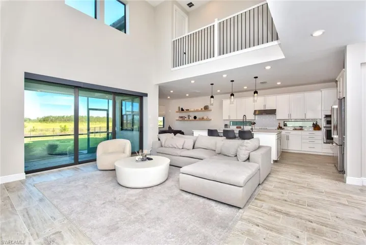 Living room featuring wood finish floors, recessed lighting, and a towering ceiling