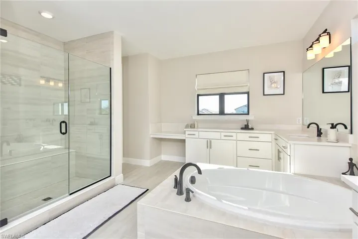 Bathroom with a garden tub, a shower stall, vanity, and light wood-type flooring
