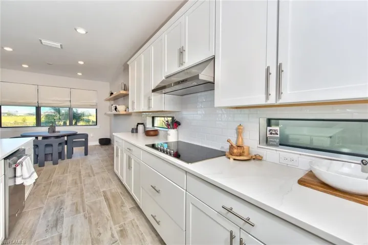 Kitchen with white cabinetry, tasteful backsplash, open shelves, recessed lighting, and under cabinet range hood